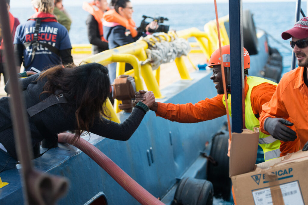 Sea-Eye - Reportage 8 Handschlag zwischen Sea Eye und Person auf anderem Boot