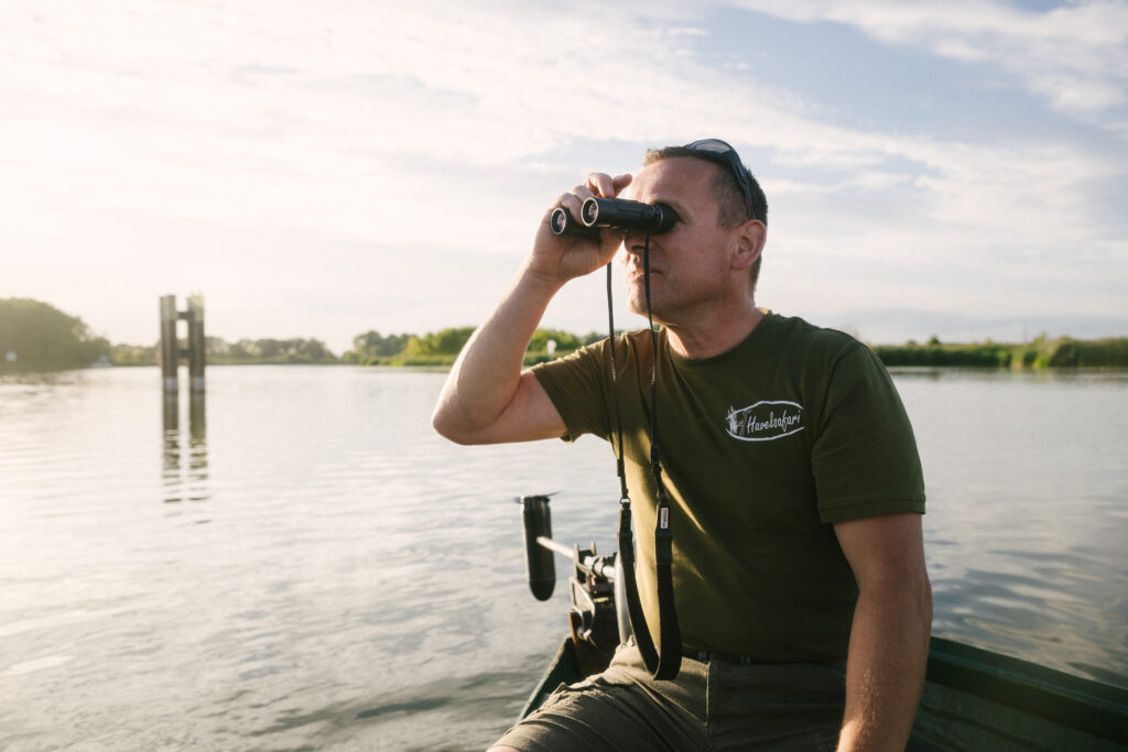 NABU Havel Renaturierung Reportage & Wildlifefotografie 18 Nabu Reportagefotografie Wildlife Havel Brandenburg Mann auf Boot schaut durch Fernglas