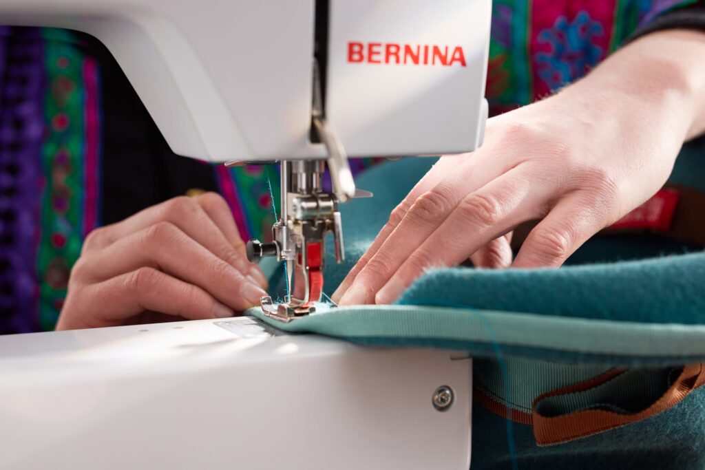 Bernina Nähmaschinen Produktfoto Bernina Nähmaschine mti Faden und händen an Hut