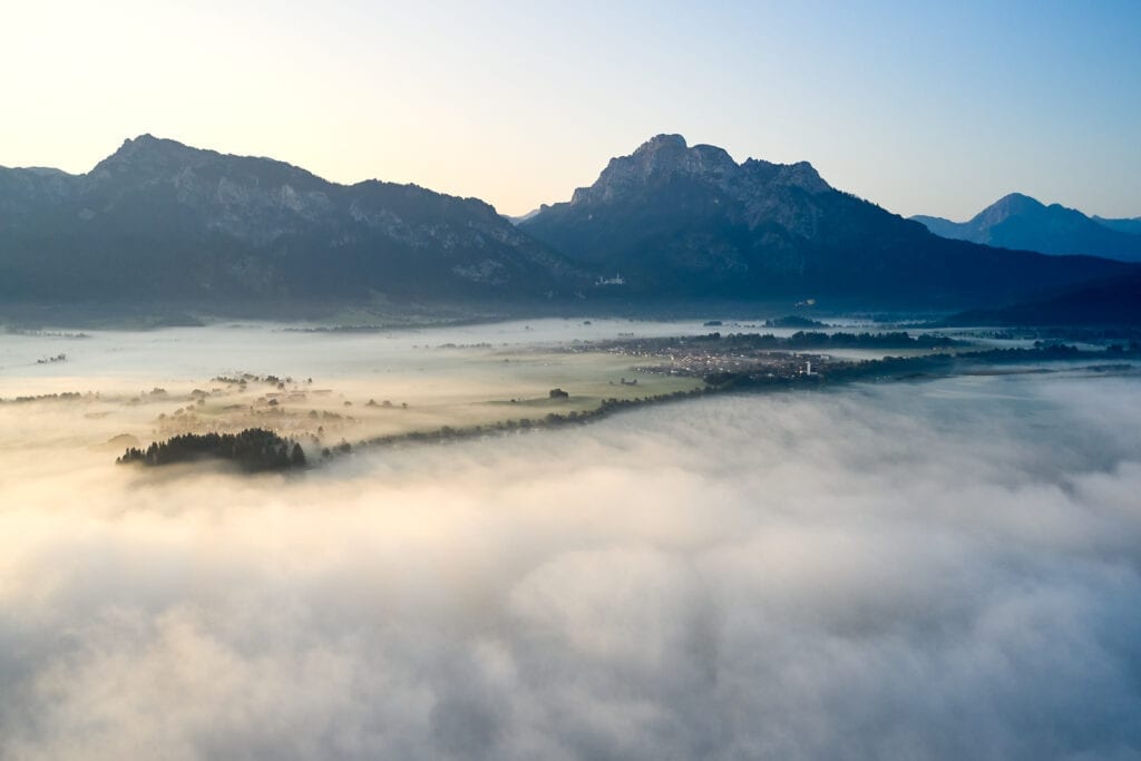 Säuling Füssen Tourismus Über den Wolken, Bild des Säulings bei Sonnenaufgang in Füssen mit Neuschwanstein