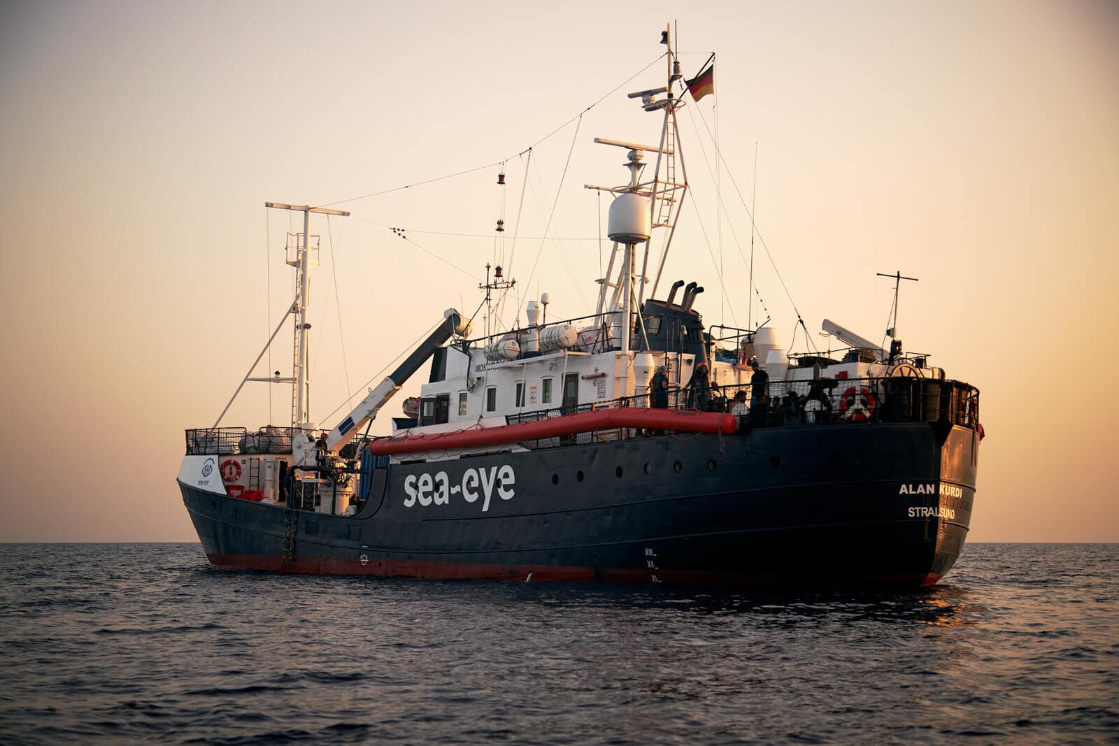 Das Rettungsschiff der NGO Sea Eye im Mittelmeer bei Sonnenuntergang mit geretteten Flüchtlingen an Bord