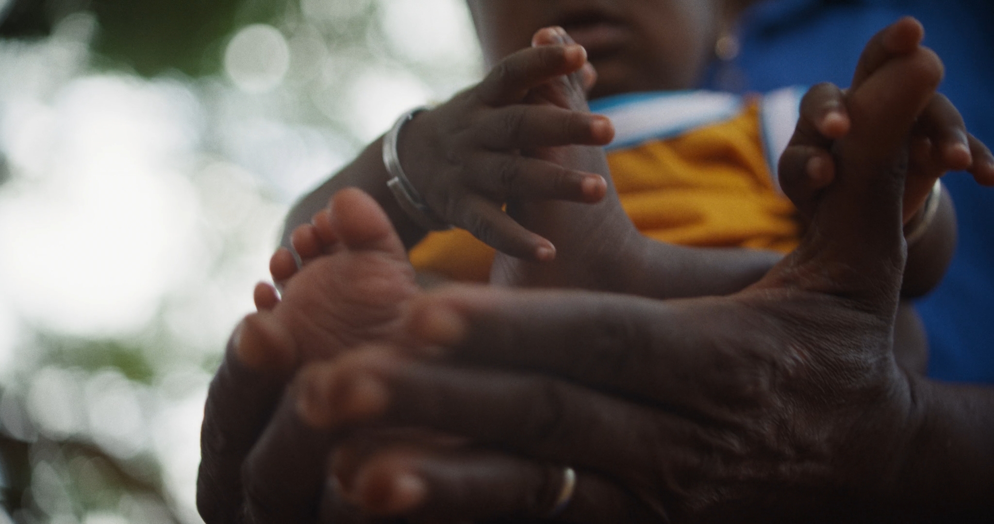 NGO Fundraising Film & Reportagen 4 Hände halten die Füße eines Babys